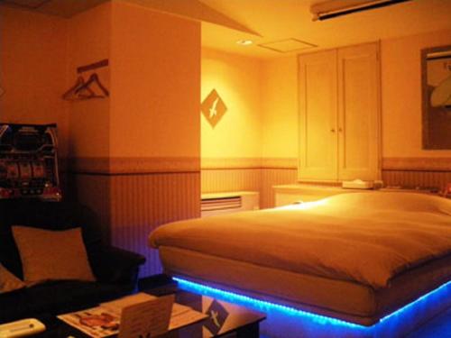 a bedroom with a bed with a blue light at Hotel Green Hill in Fukaya