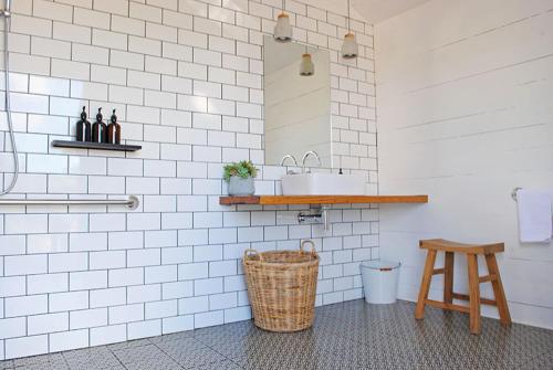 a white tiled bathroom with a sink and a stool at Cosy Tents - Daylesford in Yandoit