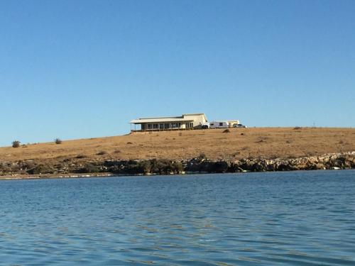 a house on top of a hill next to the water at Shades of Blue Eco Retreat in Calca