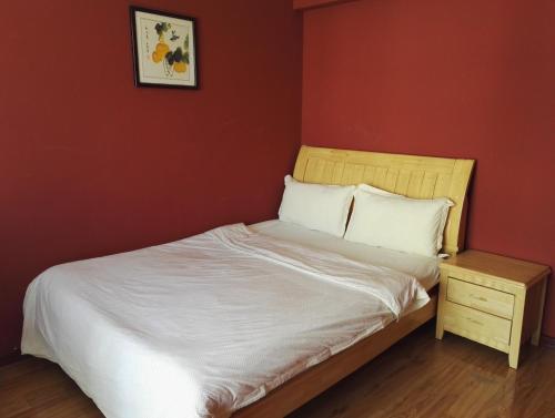a bed in a room with a red wall at LETE Hostel in Xining