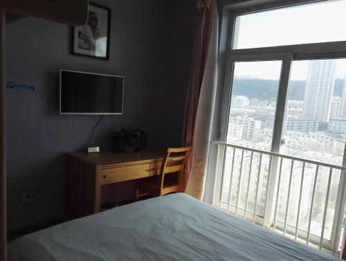 a bedroom with a bed and a desk and a window at LETE Hostel in Xining