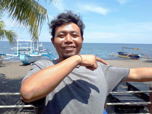 a man standing on the beach near the ocean at Gede Homestay in Lovina