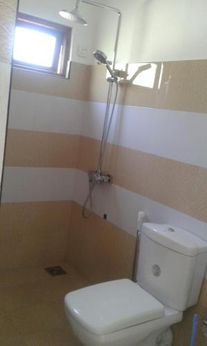a bathroom with a white toilet and a window at Lilly Guest Inn in Haputale