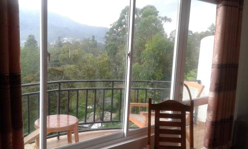 a room with a balcony with a view of trees at Lilly Guest Inn in Haputale