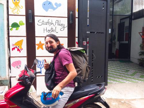 a man sitting on a scooter in front of a building at Starfish Alley Hostel in Da Nang