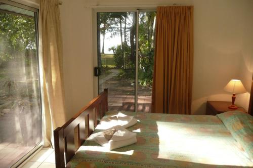 a bedroom with a bed and a sliding glass door at Beachside Holiday Units in Bowen