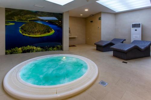 una gran bañera de hidromasaje en una habitación con una pintura en Hospederia Hurdes Reales, en Las Mestas