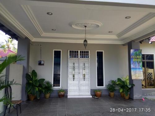 a room with a white door and potted plants at Relaxs Homestay in Kota Bharu