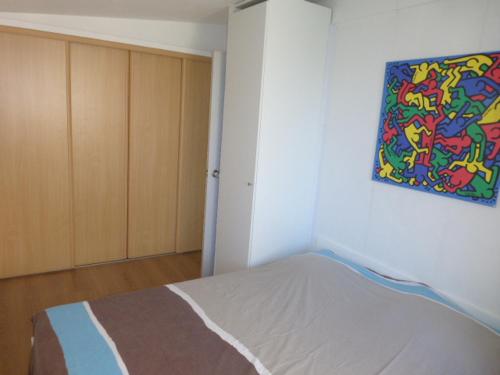 una camera da letto con un letto e un dipinto sul muro di Appartement Iris a De Haan
