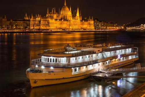 a large boat in the water in front of a building at Grand Jules - Boat Hotel in Budapest