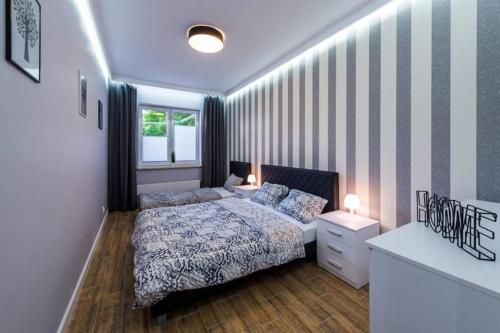 1 dormitorio con cama y pared a rayas en Apartament Żeglarska Loft U4, en Giżycko