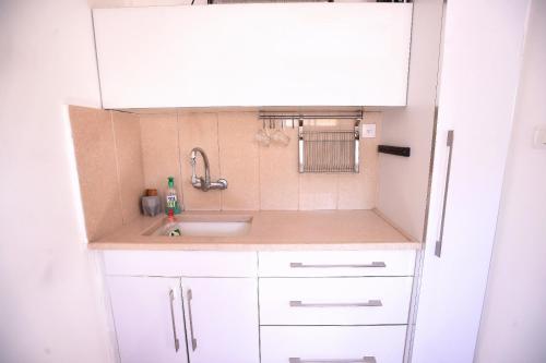 a small kitchen with white cabinets and a sink at Blue Sky in Ashkelon in Ashkelon