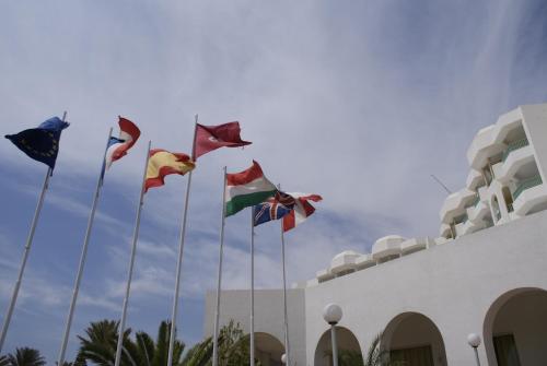a group of flags on poles in front of a building at El Mouradi Hammamet in Hammamet