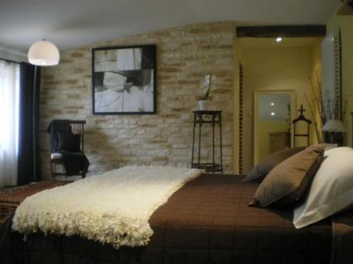 a bedroom with a large bed and a brick wall at Logis Hotel La Grange Du Relais in Colombey-les-deux-Églises