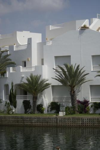 a large white building with palm trees in front of it at El Mouradi Hammamet in Hammamet