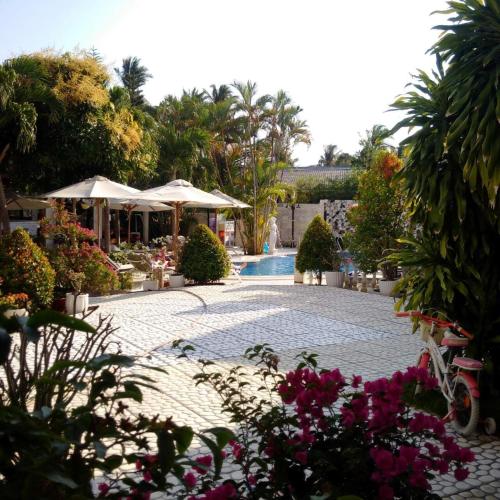 a courtyard with a pool and some flowers and umbrellas at Godiva Villa Phu Quoc in Phu Quoc