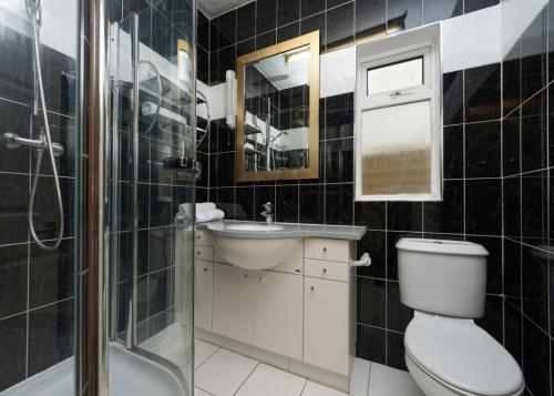 La salle de bains est pourvue de toilettes, d'un lavabo et d'une douche. dans l'établissement Golders Green Hotel, à Londres