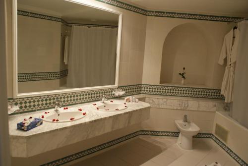 a bathroom with two sinks and a mirror and a toilet at El Mouradi Hammamet in Hammamet