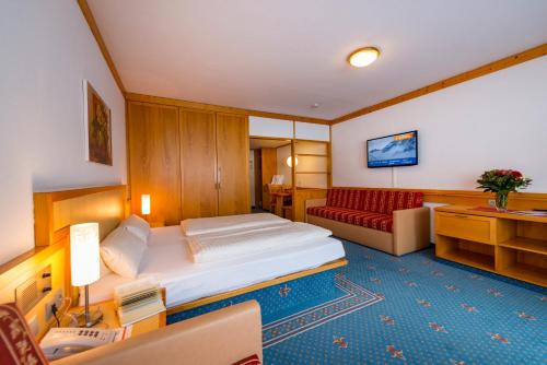 a hotel room with a bed and a couch at Alpensporthotel Mutterberg in Mutterbergalm