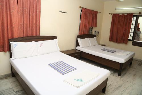 2 camas en una habitación con cortinas rojas en Star Residency, en Chennai