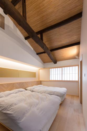 deux lits dans une chambre avec un plafond en bois dans l'établissement BenTen Residences, à Kyoto