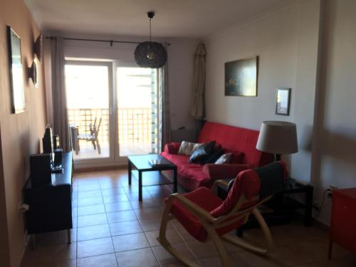 ein Wohnzimmer mit einem roten Sofa und einem Fenster in der Unterkunft Apartamento Mirador de Castilnovo in Conil de la Frontera