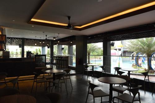 a restaurant with tables and chairs and a large window at Vangohh Eminent Hotel & Spa in Bukit Mertajam