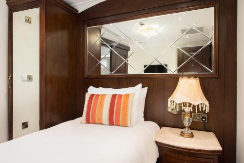 a bedroom with a bed with a mirror and a lamp at The George Street Hotel in Oxford