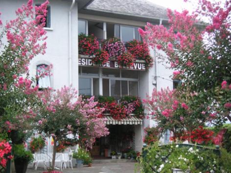 a white building with pink flowers in front of it at Le Bellevue in Agos-Vidalos