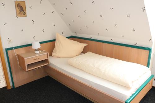 uma pequena cama num quarto com mesa de cabeceira em Gaststätte Feldkamp em Hinte