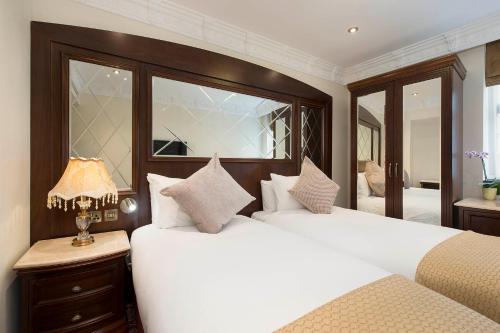 a bedroom with two white beds and a mirror at The George Street Hotel in Oxford
