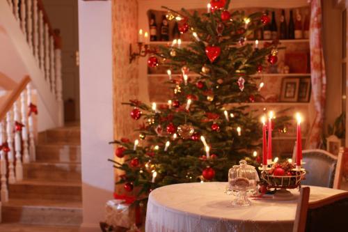 a christmas tree in a room with a table with candles at Weißt Du noch - Gästehäuser & Suiten in Kühlungsborn