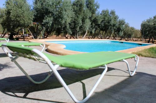 a green and white chair next to a swimming pool at Casas Rurales el Palomar in Ossa de Montiel