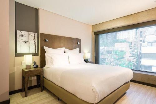 a bedroom with a large bed with a large window at Hotel CityFlats in Bogotá