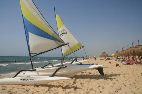 two sailboats on a beach with people on the beach at El Mouradi Hammamet in Hammamet