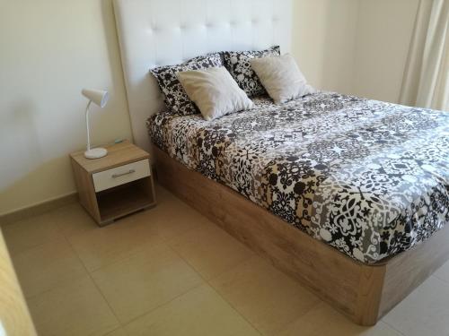 a bedroom with a bed and a night stand with a lamp at T1Encosta da Marina-Lagos in Lagos