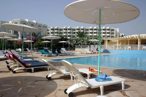 a group of chairs and umbrellas next to a swimming pool at El Mouradi Hammamet in Hammamet