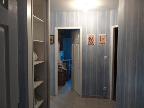 un couloir avec une chambre aux murs bleus et une porte dans l'établissement comme chez vous, à Taussat-les-Bains