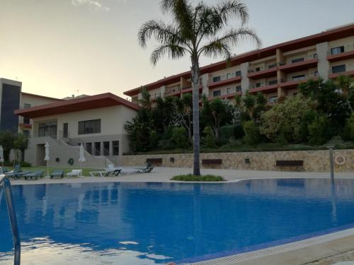 a swimming pool with a palm tree in front of a building at T1Encosta da Marina-Lagos in Lagos