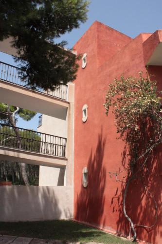 a red building with a tree on the side of it at Es Baulo Petit Hotel in Can Picafort