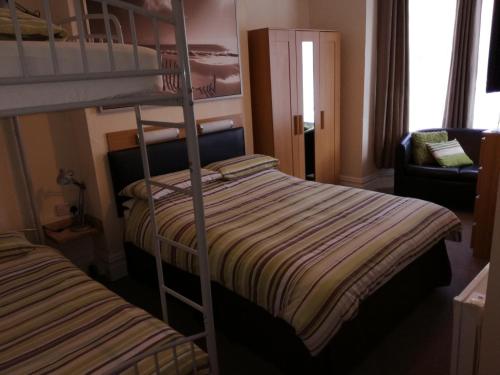 a bedroom with two bunk beds and a chair at Driftwood B&B Weymouth in Weymouth