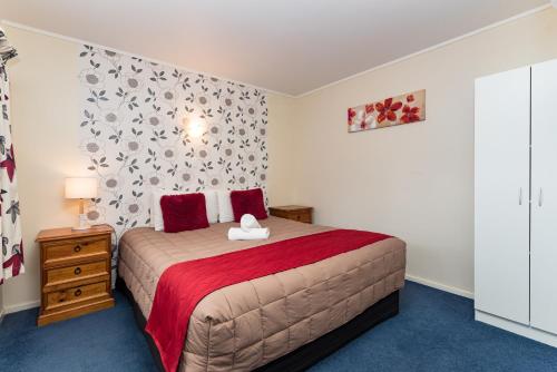 a bedroom with a bed with a red blanket at Dolphin Motel in Paihia