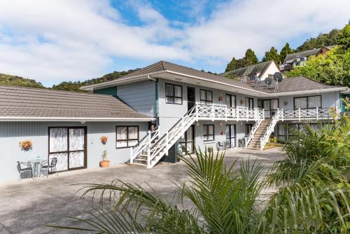 Cette grande maison blanche dispose d'une terrasse couverte et d'escaliers. dans l'établissement Dolphin Motel, à Paihia