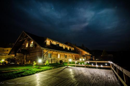 a wooden house with lights in front of it at night at Czarna Owca in Istebna