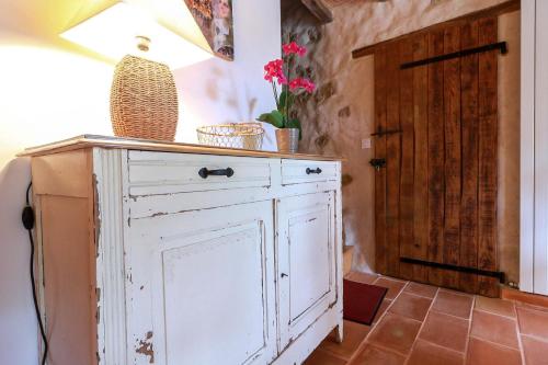 a white cabinet with a lamp and flowers on top at Gites Souleilla de la Nine in Canens