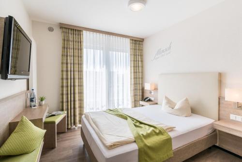 a bedroom with a bed and a large window at Parkhotel Pfarrkirchen in Pfarrkirchen