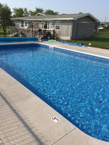 a large blue swimming pool in front of a house at Dreamweavers Cottages and Home Place Vacation Home in Rustico