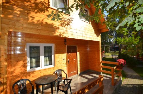 Una cabaña de madera con una mesa y sillas en el porche. en Ośrodek 9Amber, en Pobierowo