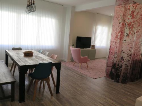 a living room with a dining table and pink chairs at Apartamento VI-VI (Vida en Vitoria) in Vitoria-Gasteiz