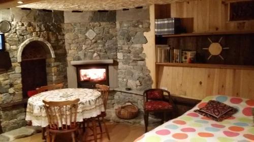 a stone fireplace in a room with a table and a fireplace at Taverna Semon in Verrayes